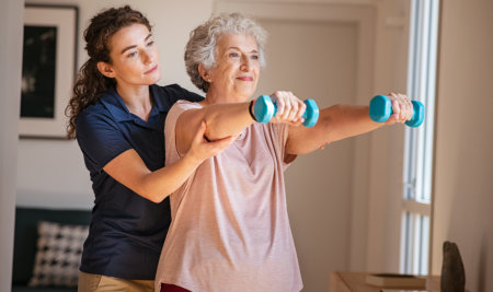 aide assisting elderly in exercising