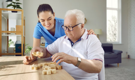 aide and elderly man playing puzzle