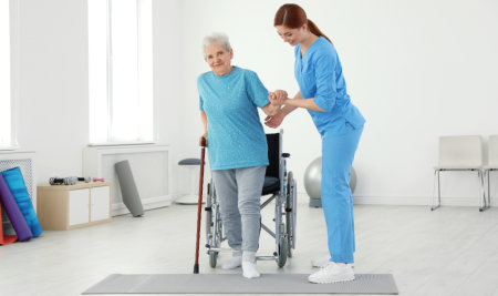 aide assisting an elderly in standing up