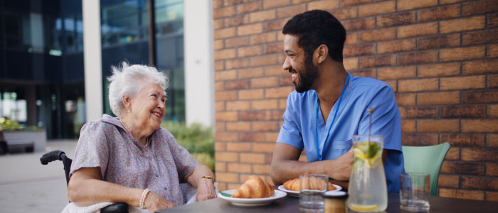 aide and elderly woman smiling at each other