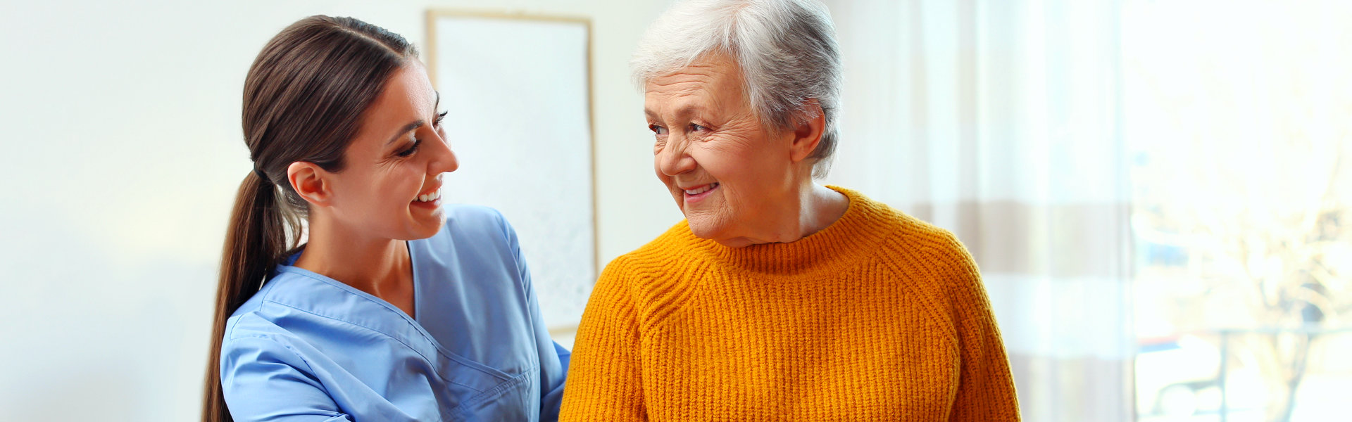 aide and elderly woman smiling at each other