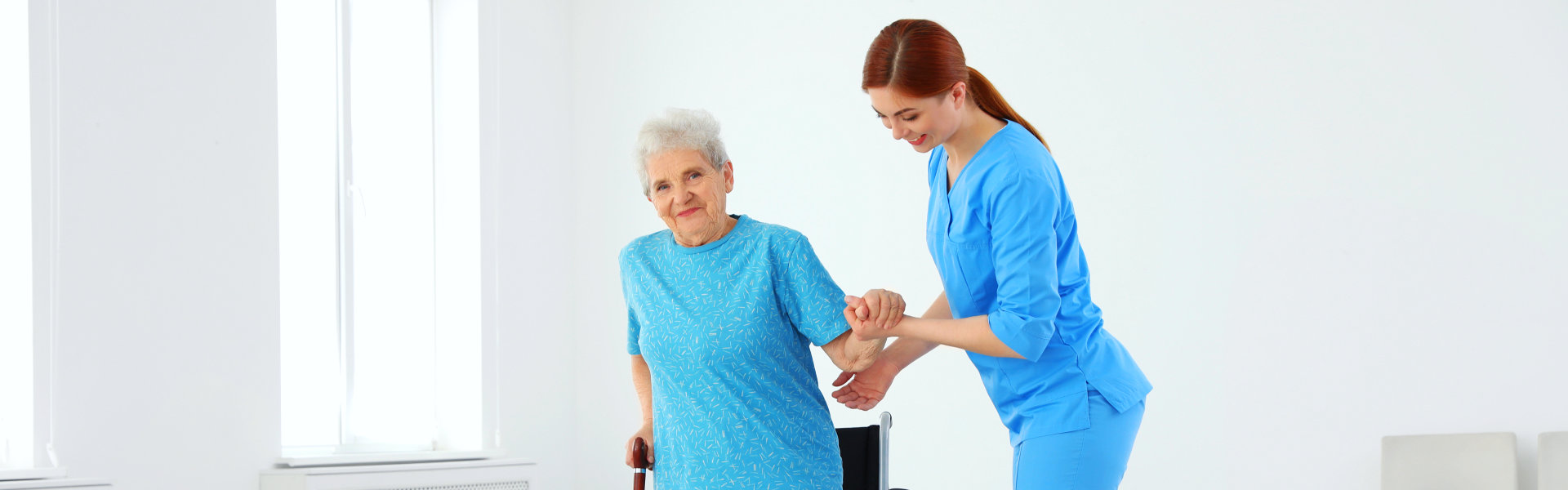 aide assisting an elderly in standing up